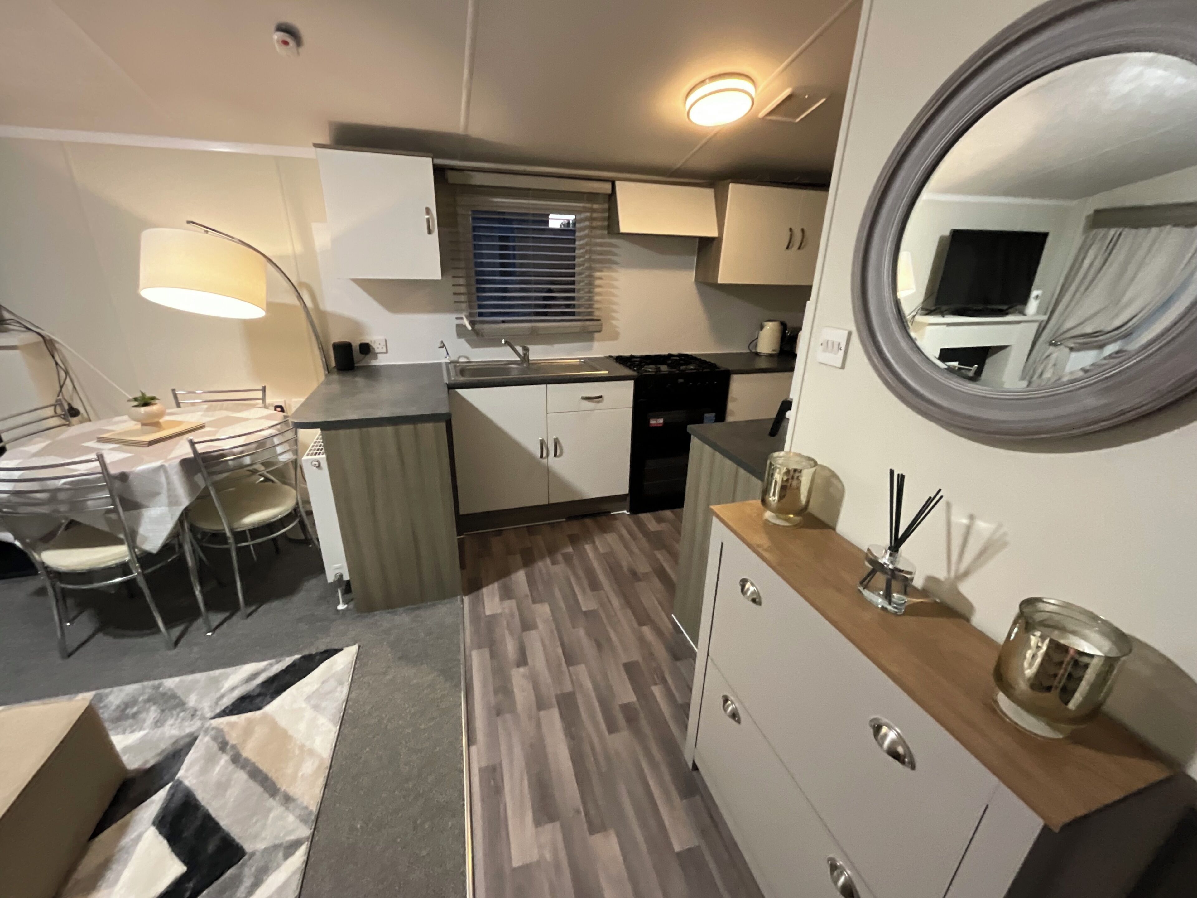 A compact kitchen with a dining area, a built-in stove, and a mirror.