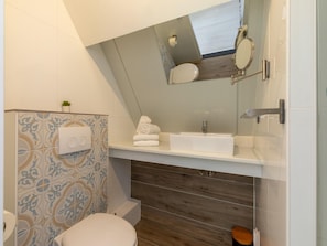 A modern bathroom with a white sink, a mirror, and a toilet.