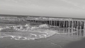 A beach with wooden groynes and waves crashing onto the shore.