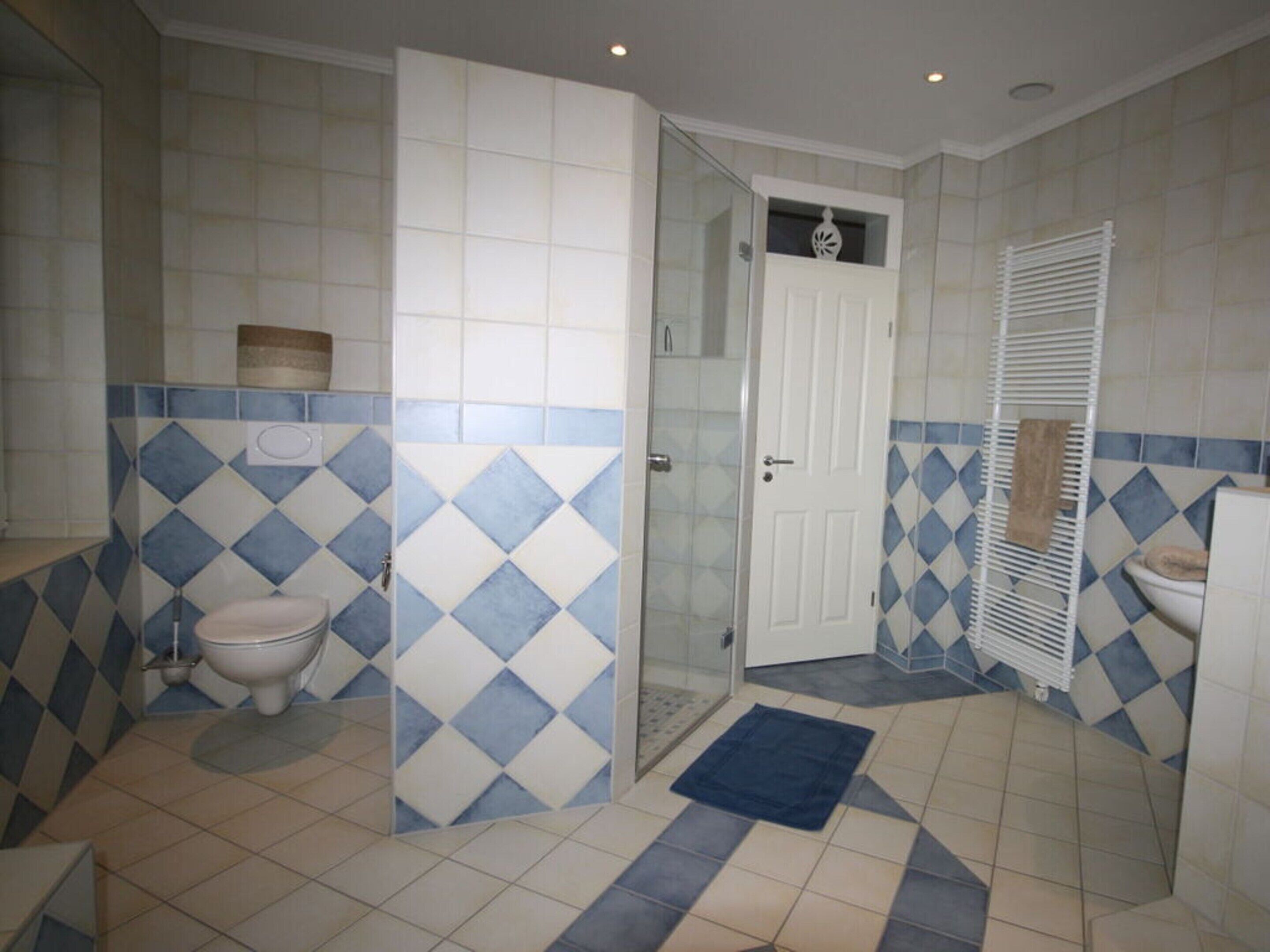 A bathroom with a toilet, shower, and sink.