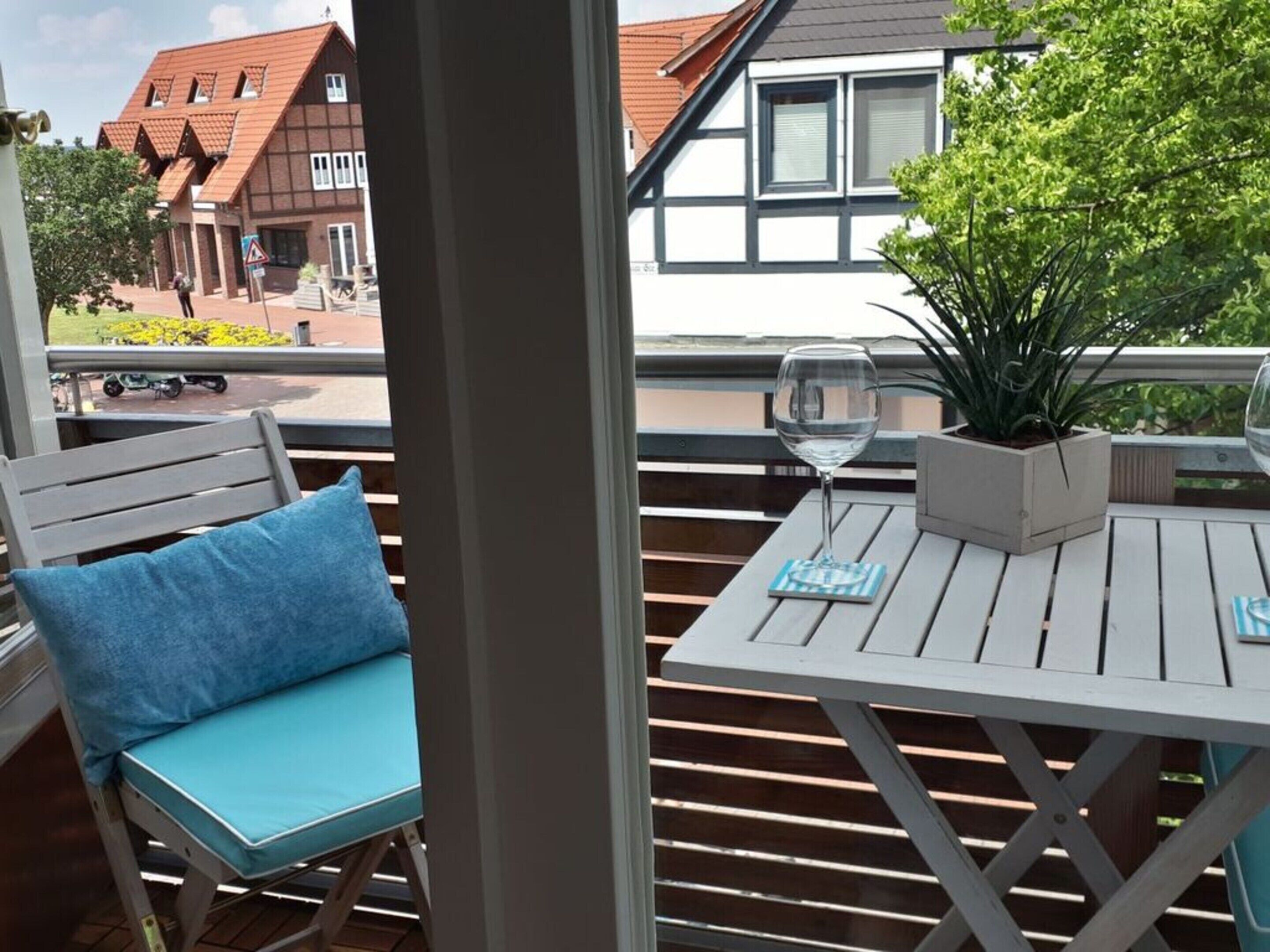 A balcony with a white table, a blue cushion, and a glass of water.