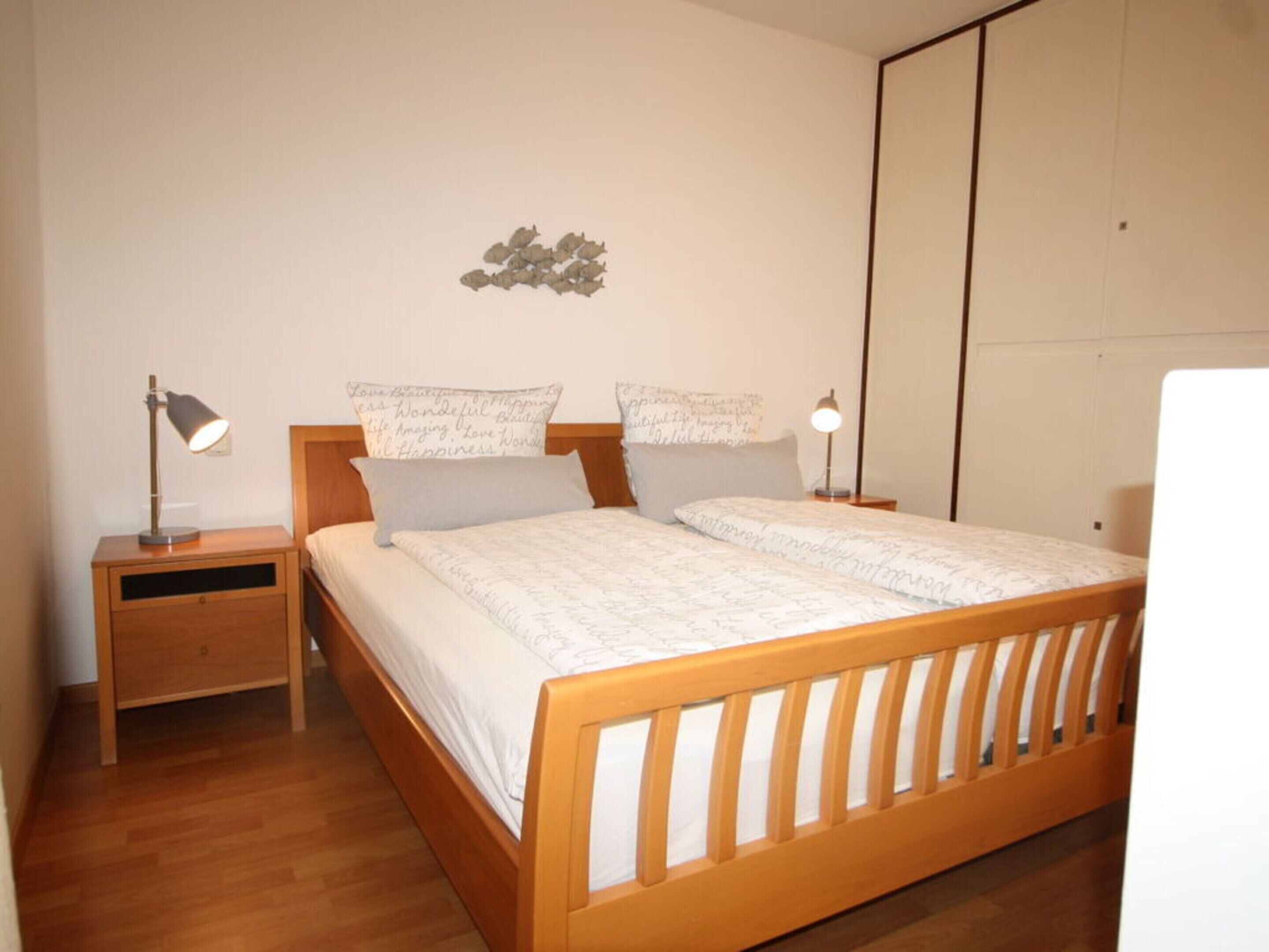 A bedroom with a wooden bed, two bedside tables, and a nightstand.