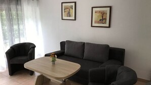 Un salon comprenant un canapé, deux fauteuils, une table basse et deux œuvres d’art encadrées accrochées au mur.