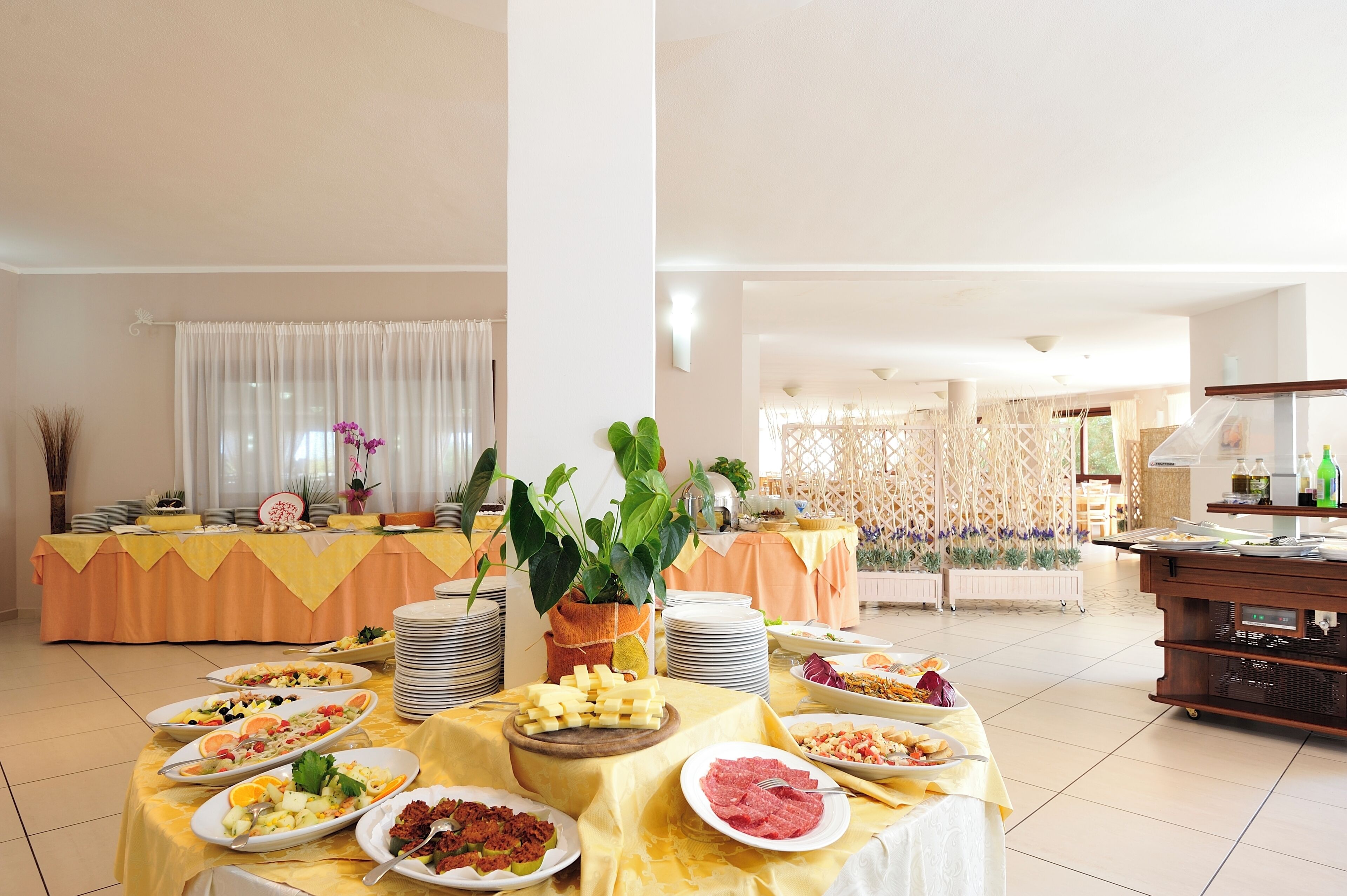 A buffet setup with various food items and a decorative plant.