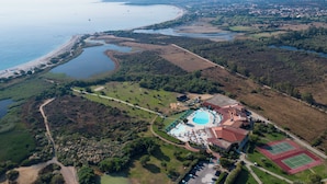 An aerial view of a resort with a swimming pool, tennis courts, and a beach. - Hotel Club Cala Fiorita (Budoni)