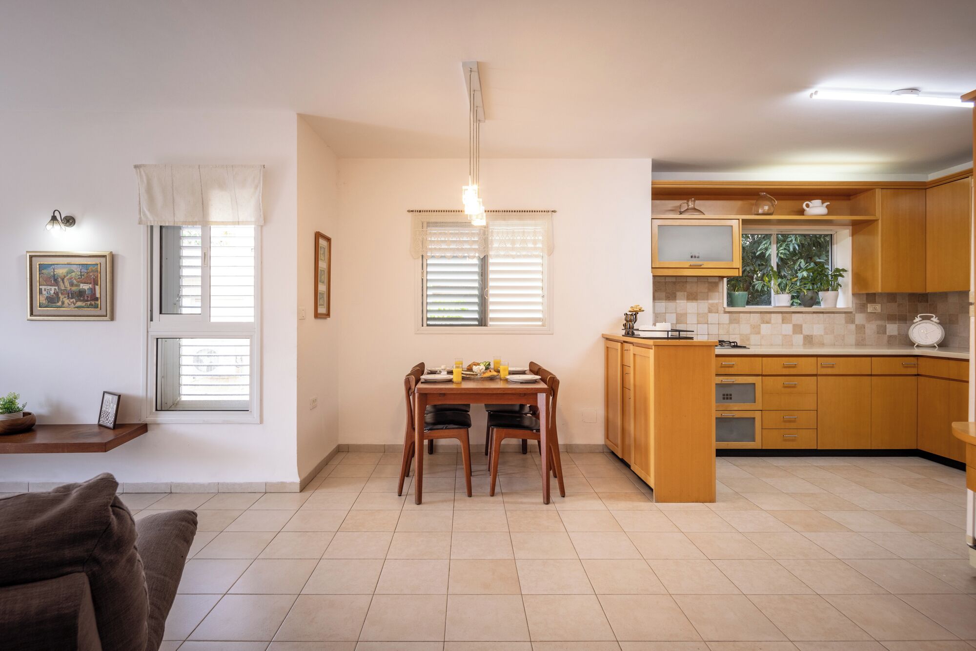 A compact kitchen with a dining area, wooden cabinets, and a tiled floor.