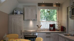 A compact kitchen with a stove, sink, and a window with a view of trees. - Cosy Apartment in Schmogrow (Schmogrow)