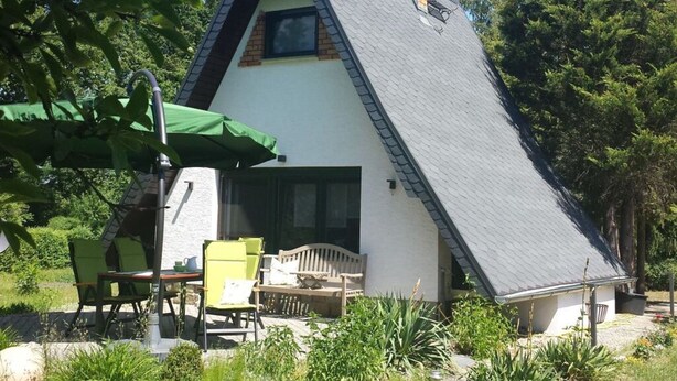 A small, triangular-shaped building with a sloped roof, a chimney, and a patio area with outdoor furniture. - Cosy Apartment in Schmogrow (Schmogrow)