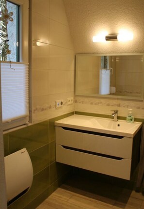 A bathroom with a white sink, mirror, and green tiles. - Cosy Apartment in Schmogrow (Schmogrow)