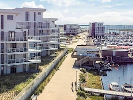 A coastal residential area with modern buildings, a marina, and a pedestrian walkway.