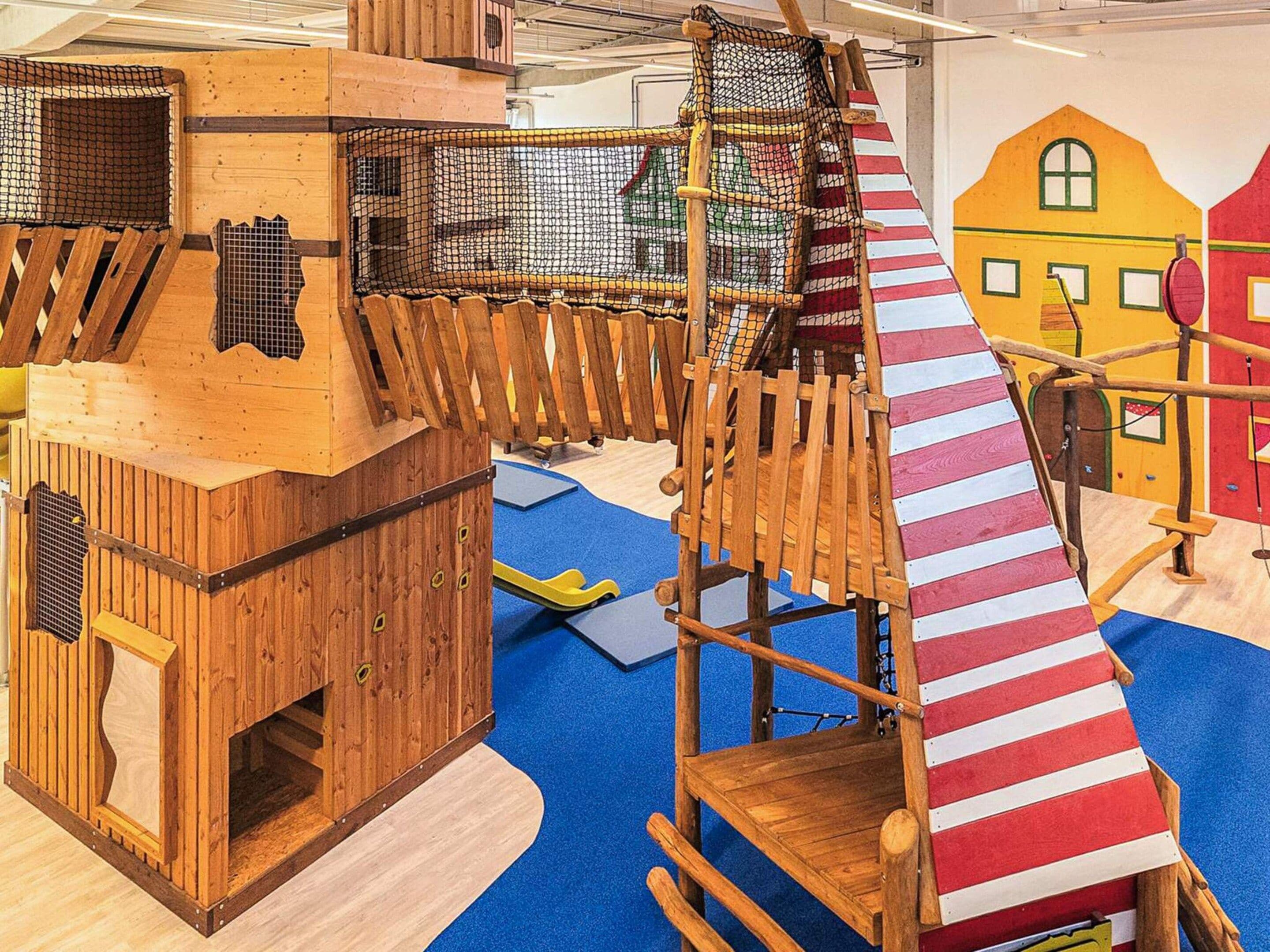 Une structure de jeu en bois, dotée d’un toboggan et d’un filet d’escalade.