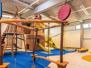 A children's play area with a wooden climbing structure, slides, and swings. - Holiday Home in Wendtorf (Wendtorf)