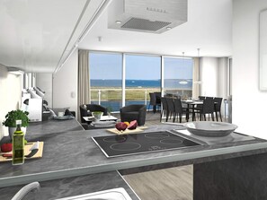 A modern kitchen with a large island, dining area, and a view of the sea. - Holiday Home in Wendtorf (Wendtorf)