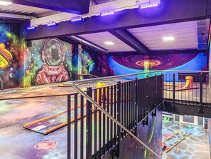 Un intérieur à thème spatial, avec une fresque murale, un escalier et un toboggan.