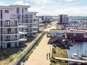 A coastal residential area with modern buildings, a marina, and a pedestrian walkway. - Holiday Home in Wendtorf (Wendtorf)