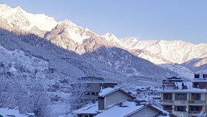 A residential area with snow-covered houses and a mountainous backdrop. - La kailasha Regency (Manali)