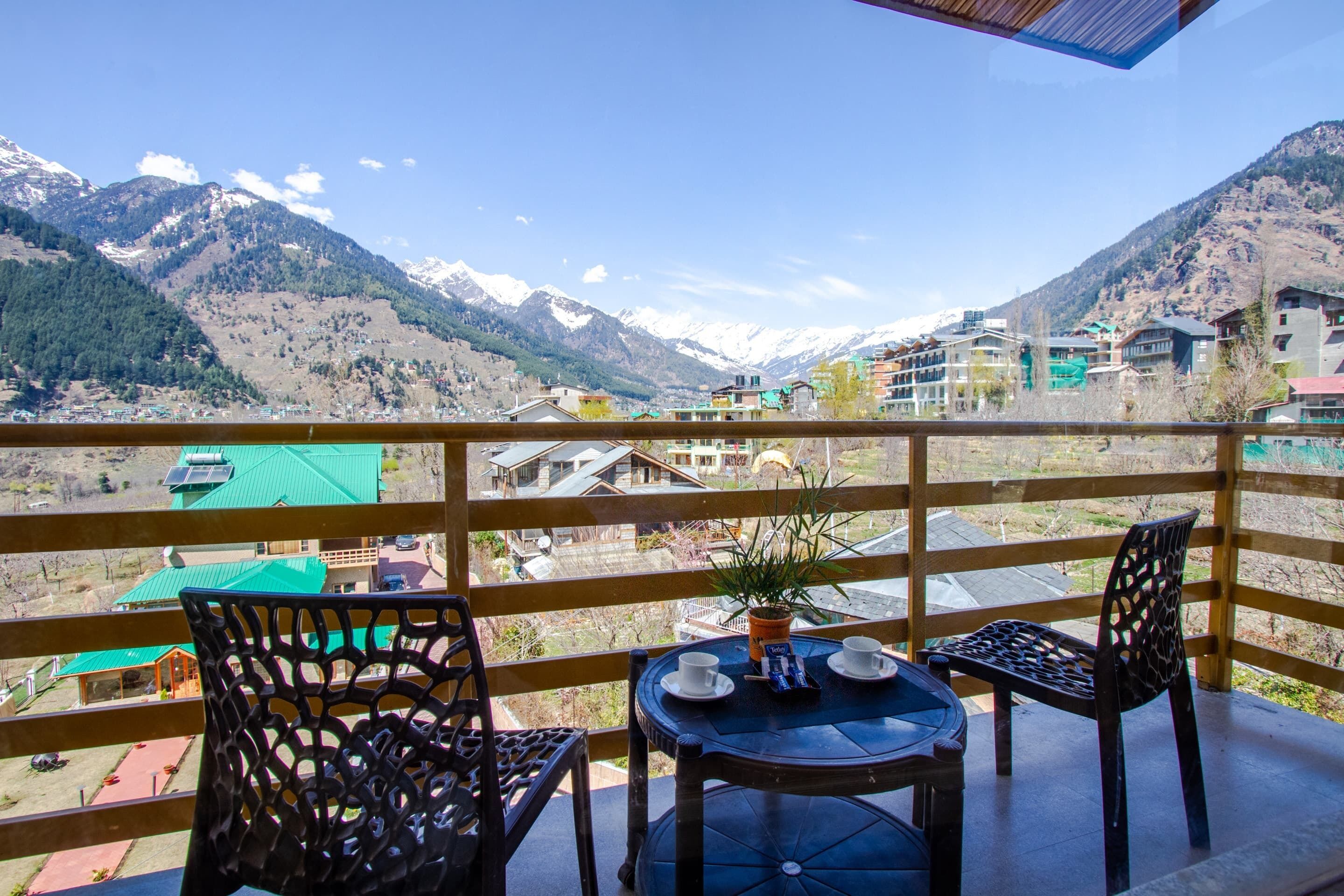 A balcony with a table and chairs overlooking a mountainous landscape.