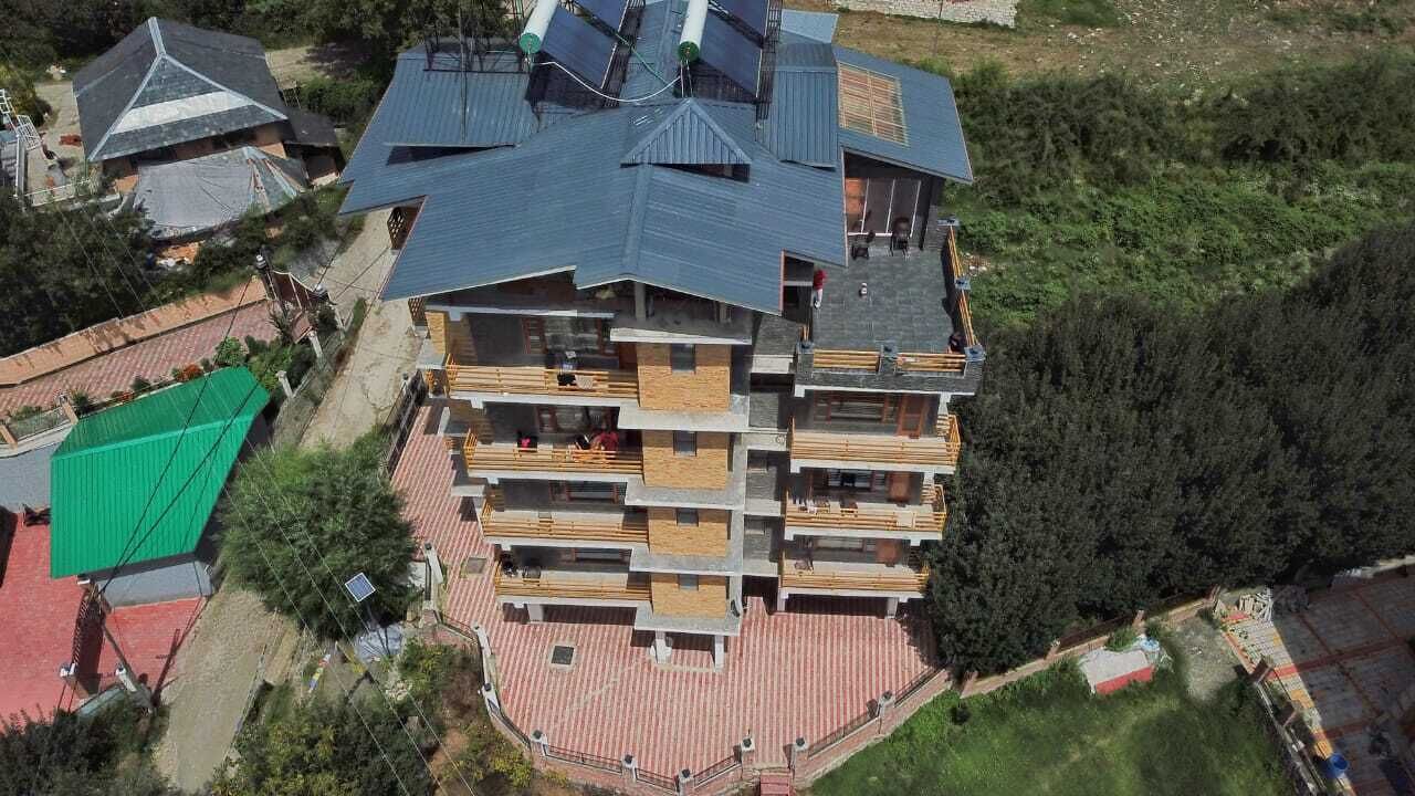 Ein mehrstöckiges Gebäude mit flachem Dach, Balkonen und einer gepflasterten Erdgeschosszone.