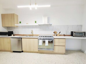 A modern kitchen with a dishwasher, stove, microwave, and wooden cabinets.