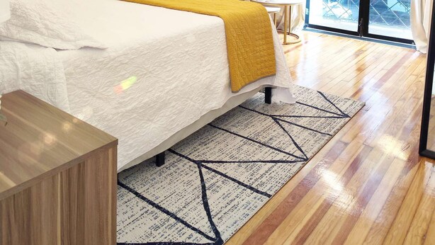 Une chambre moderne avec un lit, un canapé, un lustre et une grande fenêtre.