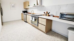 Une cuisine moderne équipée d’une cuisinière à gaz, d’un four, d’un four à micro-ondes et d’un grille-pain encastré.