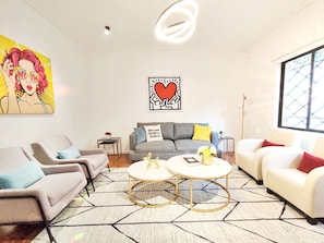 A modern living room with two sofas, a coffee table, and a painting on the wall.