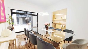 Un coin repas moderne avec une table en verre, six chaises et un vase de fleurs.