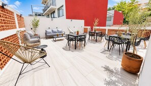 A rooftop patio with outdoor seating, including a sofa and multiple tables and chairs.