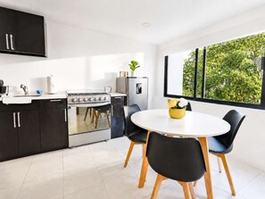 Una cocina moderna con estufa, refrigerador y comedor con sillas y una mesa.