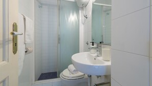 Une salle de bain équipée d’une douche, de toilettes, d’un lavabo et d’un miroir.