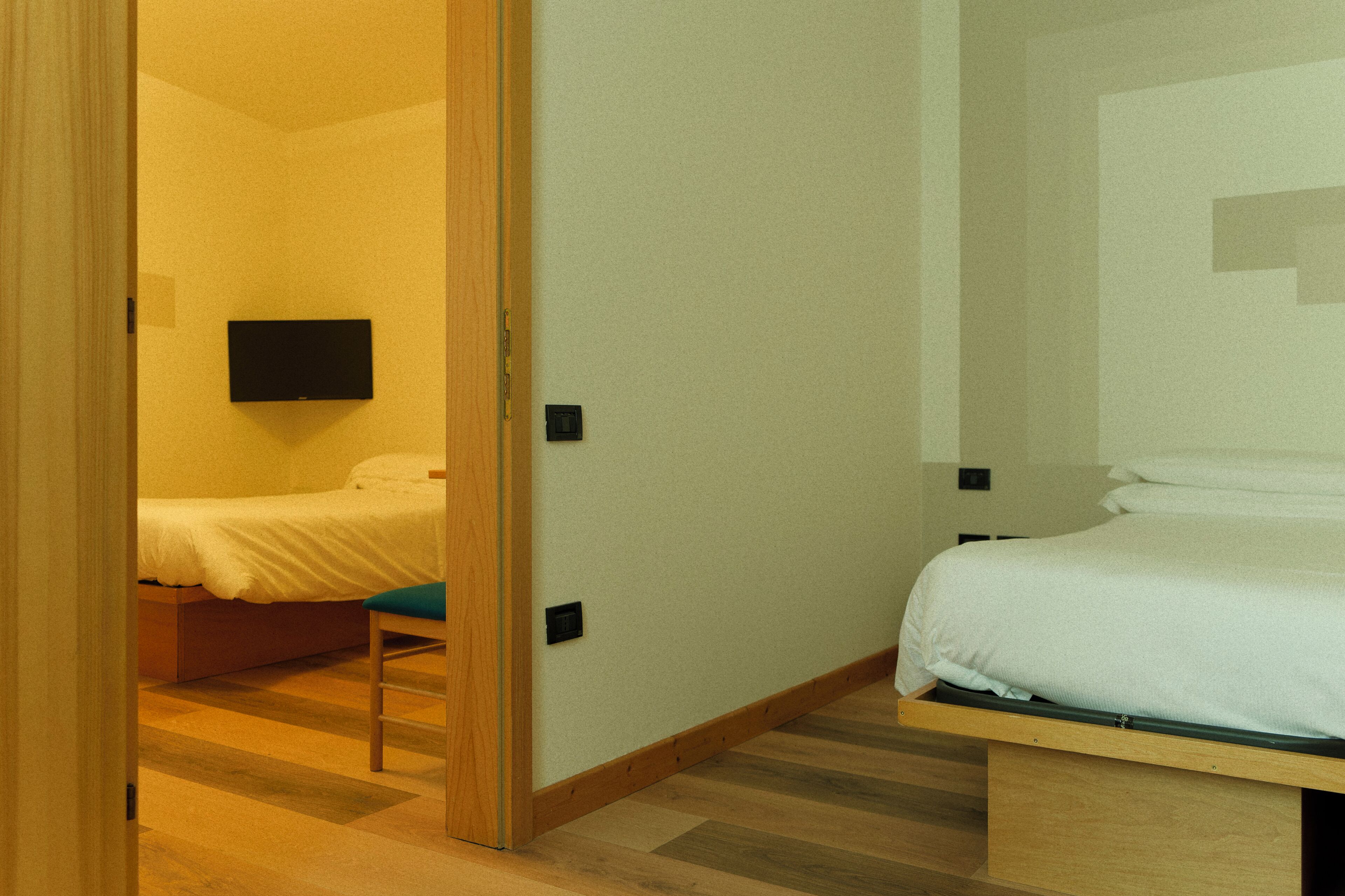 A bedroom with a bed, a chair, and a television mounted on the wall.