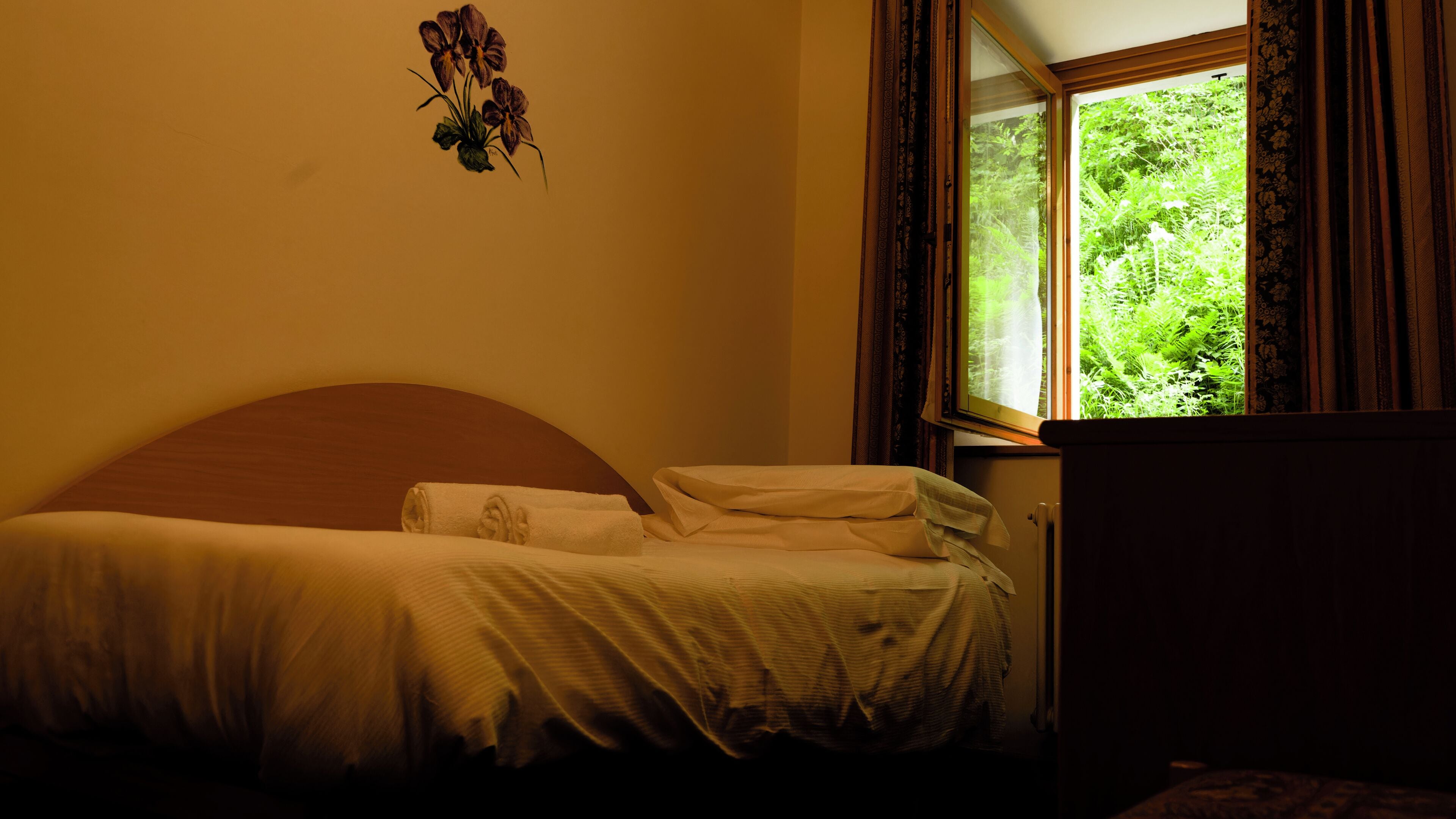 A bedroom with a bed, a window with curtains, and a wall-mounted decoration.