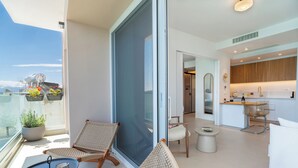 Een balkon met rieten stoelen, een klein tafeltje en potplanten.