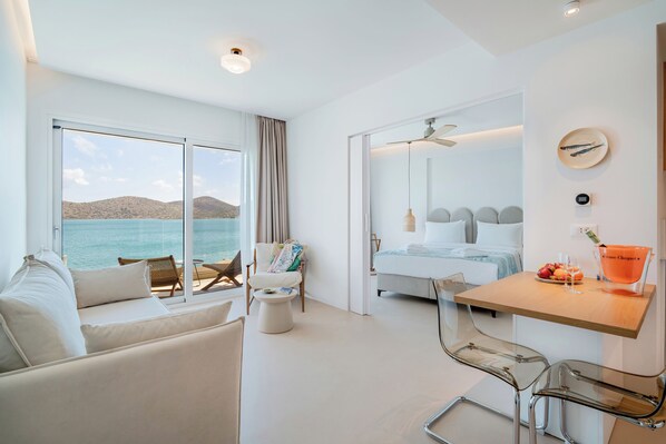 Une chambre d’hôtel moderne dotée d’un balcon, d’un lit, d’un coin repas et offrant une vue sur la mer.