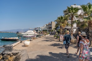 A coastal promenade with boats docked, a clear sky, and buildings along the waterfront. - Ocean Rythm Elounda Apartment (Elounda)