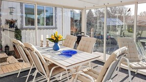 A sunroom with a table and chairs, large windows, and a view of the outdoors. - 4 Star Holiday Home in Lysekil (Lysekil)