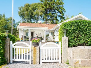 A two-story house with a red-tiled roof, a white fence, and a garden with potted plants. - 4 Star Holiday Home in Lysekil (Lysekil)