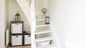 A white staircase with a metal railing, leading to a landing area with wicker baskets and a black metal lantern. - 4 Star Holiday Home in Lysekil (Lysekil)