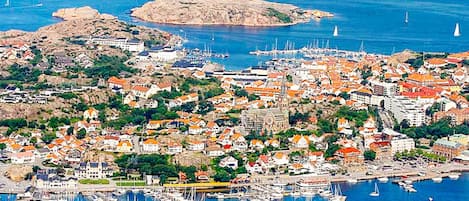 A coastal town with a marina filled with boats, surrounded by residential buildings with red roofs.