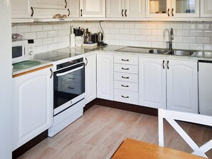 A kitchen with white cabinets, a microwave, an oven, a sink, and a wooden countertop.