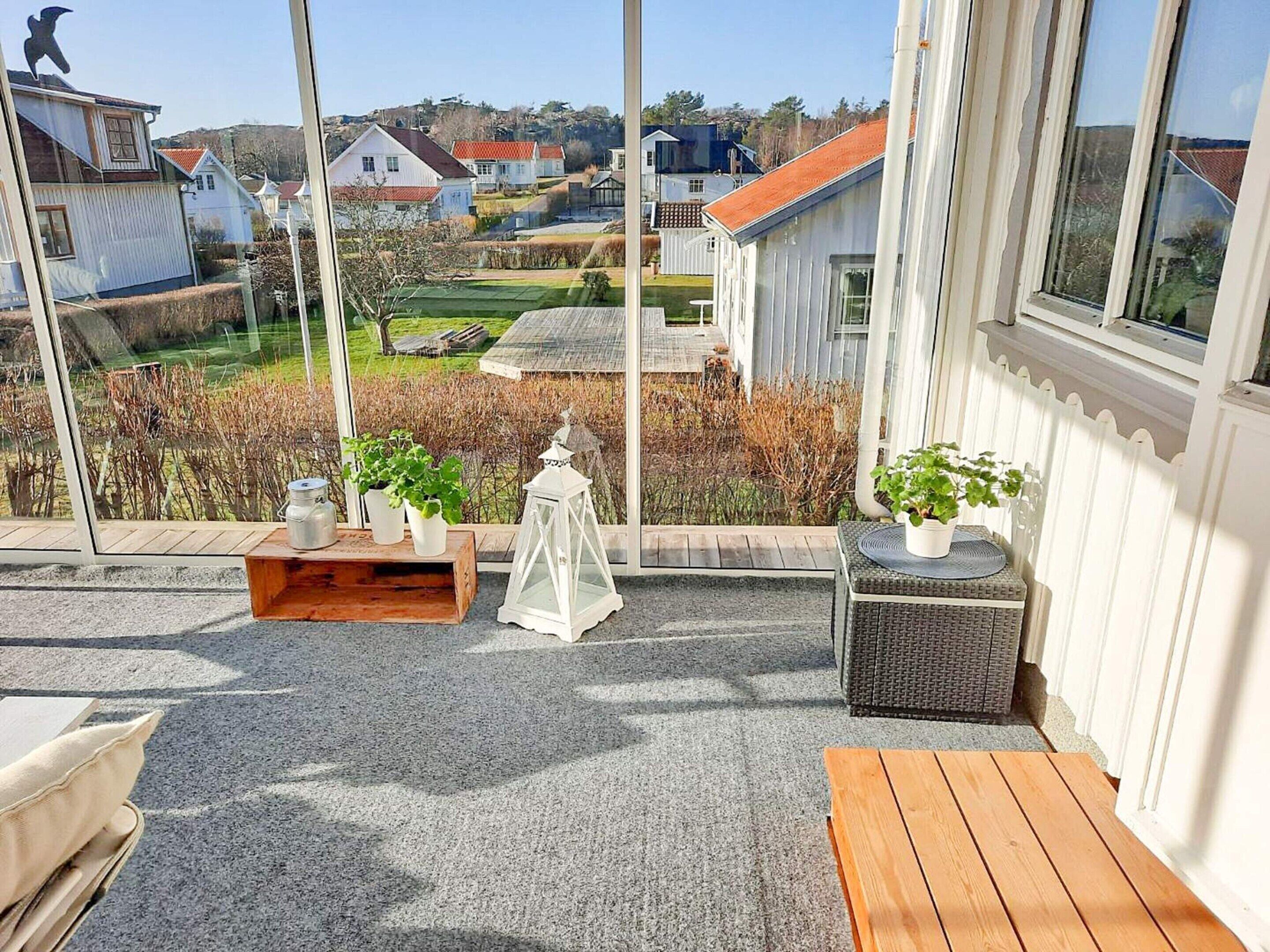 A covered outdoor seating area with a view of houses and a garden.