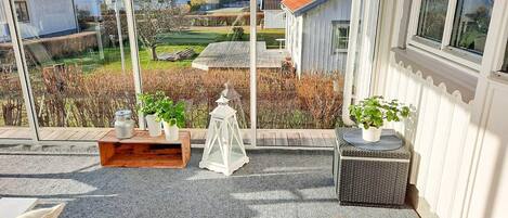 A covered outdoor seating area with a view of houses and a garden.