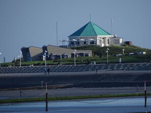 A building with a green roof, a seating area, and a view of the water. - Appealing Apartment Near Town Center (Norderney)