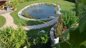 Ein Gewächshaus mit Teich, umgeben von einem gepflegten Garten und einem gepflasterten Weg.