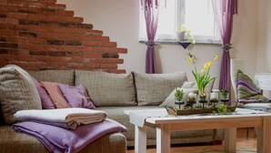 Ein Wohnzimmer mit Backsteinwand, einer Couch, einem Couchtisch und einem Fenster mit Vorhängen.