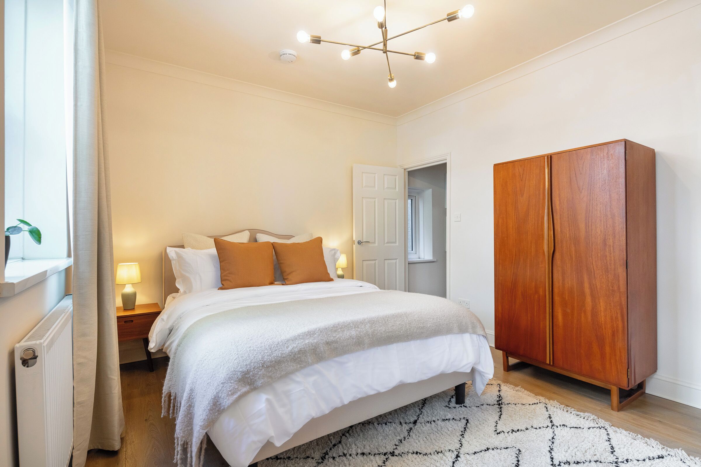 Ein Schlafzimmer mit einem Bett, Nachttischen, einem Kleiderschrank und einer Deckenleuchte.