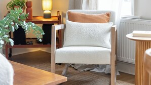 A cozy living room with a white armchair, a small wooden table, a lamp, and a potted plant. - Centrally located Scandinavian high quality design. 2 min walk to station (London)
