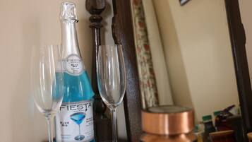 Una botella de champán Fiesta Blue Mix, dos copas y un recipiente de cobre sobre una superficie de madera.