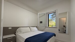 Une chambre à coucher avec un lit, une table de chevet, une fenêtre et un miroir.