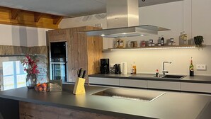 A modern kitchen with a wooden island, stainless steel appliances, and a built-in sink. - Gemütliches Ferienhaus für Große Familien und Gruppen (Kell am See)